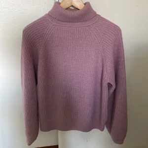 Ljuslila polotröja från Name It - Mysig ljuslila polotröja från Name It, stickad i ett grovt ribbat mönster. Tröjan har hög polokrage och långa ärmar, perfekt för kyliga dagar. Enkel och stilren design. Den är endast använd 2-3 gånger 
