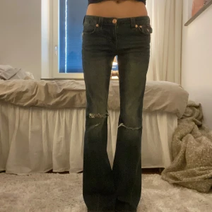 True Religion Joey Low Rise Flare Jeans - Säljer ett par blåbruna True Religion Joey jeans med  klassiska orange sömmar, slitningar vid knäna och snygga bakfickor med lock, de är använda bara ett par gånger då de är köpta för 1 599kr där av priset 💕midjemåttet är 38cm rakt över, innerbenslängden är 81cm💕skriv om du vill ha fler bilder eller frågor💕