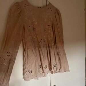 Beige blommig blus från & Other Stories - Säljer en beige blus från & Other Stories Paris Atelier med broderade blommor och spetsdetaljer. Blusen har långärmade puffärmar, rund hals och vackra broderier både fram och på ärmarna. Materialet är linne och ger en luftig känsla. Perfekt för dig som gillar romantisk stil.