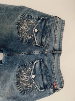 Low rise flared jeans  - Säljer dessa lågmidjade bootcut jeans med broderi och kristalldetaljer på fickorna (tvättas ut och in). Stretchigt material med midjemått 42cm tvärs över och innerbenslängd 80cm. Vid snabb affär kan pris diskuteras 🫶🏻