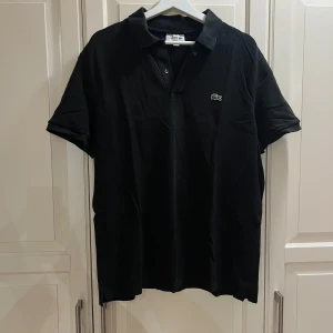 Svart piké Lacost  - Svart piké slim fit från Lacoste i 100% bomull. Nypris: 1350kr.