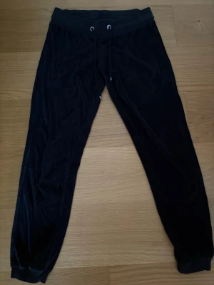 Svarta mjukisbyxor med snörning - Svarta mjukisbyxor från Cubus i storlek M med mjukt och lent tyg som ger en skön känsla. Byxorna har resår och snörning i midjan samt ribbade muddar vid bensluten. Perfekta för chill eller häng med kompisar. 80% Bomull, 20% Polyester. 