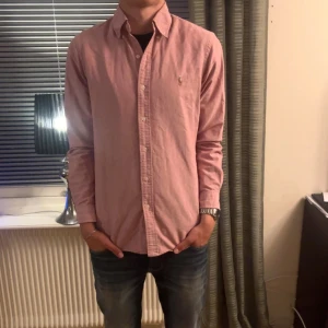 Rosa skjorta från Ralph Lauren - Säljer en snygg rosa skjorta från Ralph Lauren i modellen Custom Fit. Skick 8,5/10 använd men inga defekter. Modellen är 185 och väger 74. Storlek S/M. Skriv för mer frågor!