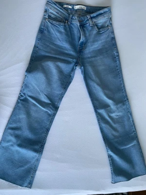 Ljusblå bootcut jeans från MANGO  - Säljer ett par ljusblå jeans från MANGO modell Sienna. Byxorna har bootcut passform, hög midja och klassisk femficksdesign. Tillverkade i mjukt jeansmaterial med dragkedja och knapp framtill. Dem är nyköpta jag har haft på mig dem bara en gång. Perfekta för en chill och trendig look.