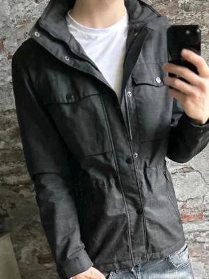 Riktigt snygg J.Lindeberg field jacka! - Säljer denna riktigt snygga J Lindeberg fieldjacket, j.lindeberg är kända för att överlägset ha de bästa field jackorna på marknaden och denna är enligt mig den bästa. Modellen är 185, 79 kg. Mycket bra skick förutom lite slitningar längst ut vid armkanten, men absolut inget som märks. Dragkedjan är tyvärr strulig men jag tycker ändå det blir snyggast när man endast använder knappar som på bilderna, vill man laga dragkedjan så går d säkert! Väldigt bra pris då dessa brukar kosta 2000 begagnat