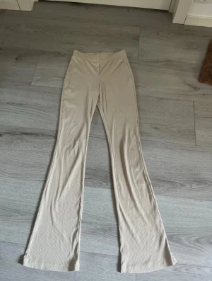 Beige ribbade bootcut-byxor Divided XS - Säljer ett par beige ribbade byxor från Divided i storlek XS. Byxorna har bootcut-modell och är tillverkade i mjukt stretchigt material med 85% polyester och 15% elastan. Hög midja och bekväm passform, perfekta till vardagslooken. Några fläckar på dom