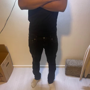 Svarta Levi's Premium jeans straight fit - Svarta jeans från Levi's Premium Jeansen har en stilren look med svarta nitar och knapp, samt Levi's-märke på bakfickan. Materialet är jeans och passformen är normal med straight fit. Som man kan se på bilden har jeansen två små hål i bakfickan. 😃 jag som är på bilden är 174 lång och väger 55kg. Skulle säga att det passar dig som är från 166 till 174.