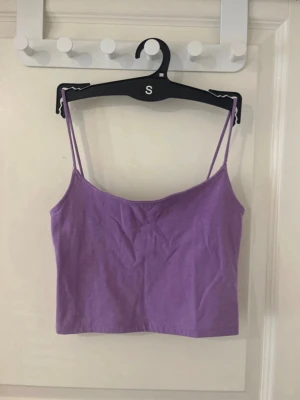 Lila croppad linnetopp från FB Sister - Säljer en lila croppad linnetopp från FB Sister i storlek XS. Toppen har tunna axelband och är tillverkad i mjuk bomull, perfekt för varma dagar. Enkel och stilren design som är lätt att matcha med jeans eller kjol.