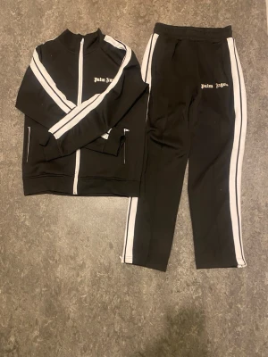 Palm Angels Tracksuit - Säljer denna klassiska tracksuit från Palm Angels, då den inte kommer till användning. Den är väl använd och är i acceptabelt skick, finns några skavanker, dock påverkas inte användningen alls. Skriv för mer info!