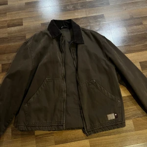 Brun workwear jacka med krage - Snygg brun workwear-inspirerad jacka med två stora framfickor och mörkare krage. Jackan har dragkedja framtill och en liten patch vid ena fickan. Jackan är från Zara och är storlek M. Priset går att diskuteras👍