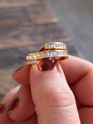 Guldfärgad ring med stenar - Säljer en snygg guldfärgad ring med två rader gnistrande stenar runt om. Storleken går att justera. Ringen är i silver och doppad i guld. Aldrig använt 