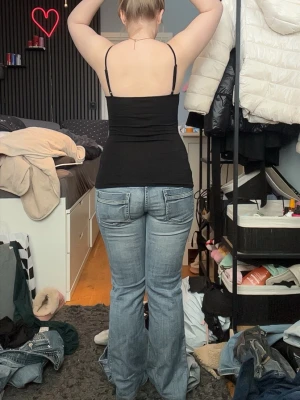 Ljusblå low waist bootcut jeans med slitningar - Säljer ett par ljusblå bootcut jeans med lätt slitna detaljer och klassisk femficksdesign. Jeansen har låg midja och en avslappnad passform över benen. Perfekta för en trendig och avslappnad look. Säljer då de är lite små för mig, pris kan diskuteras.