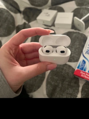 Apple AirPods Pro med laddningsetui - Säljer ett par vita Apple AirPods gen 3 med trådlöst laddningsetui. De har en stilren och kompakt design med silikonproppar för extra komfort. Perfekta för dig som vill ha grymt ljud och smidig anslutning till din iPhone eller andra Apple-enheter.Vänster öra hörs musiken lite lägre i än höger 