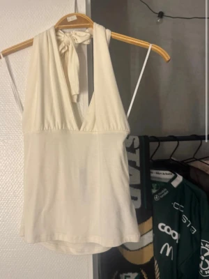 Vit halterneck linnetopp med knyt - Säljer en snygg vit linnetopp med halterneck och knyt i nacken. 