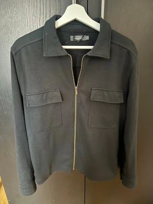 Overshirt från dressman - En svart overshirt från dressman i storlek small, allmänt använd men helt felfri. Vid fler frågor eller funderingar är det bara att höra av dig!