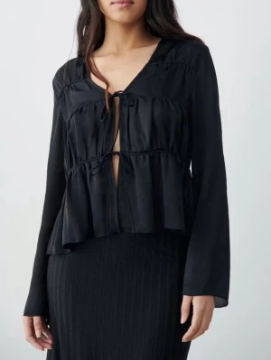 Svart blus med knytning framtill - Trendig svart blus med v-ringning och knytning framtill.  Sparsamt använd!