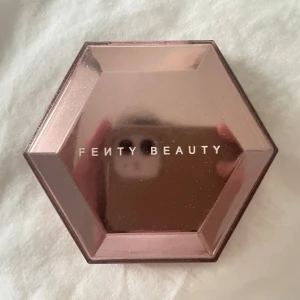 Fenty Beauty highlighter How many carats - Supersnygg highlighter från Fenty Beauty i en glansig, roséguldig hexagonformad dosa med spegel. Själva highlightern är vit med en skimrande finish som ger ett riktigt glow. Perfekt för att framhäva kindben och ge extra lyster till din look. Skickas nästa vardag.  Obs: den är 2 år gammal. Skick enligt bild. 