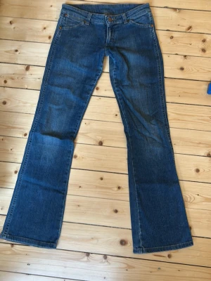 Blå bootcut jeans från Wrangler - Snygga blå lågmidjade bootcut jeans från Wrangler med jätte bra skick! Säljer pga att de är för korta för mig innerbenslängden är 76cm och midjemåttet tvärs över är 37 cm. De passar mig i midjan som har storlek 34!💓
