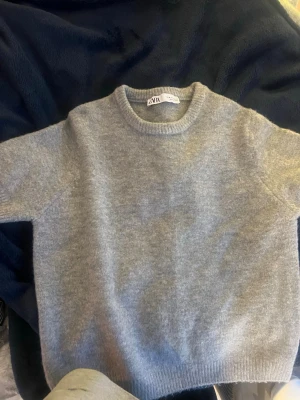 Grå stickad tröja från Zara - Mysig grå stickad tröja från Zara med rund halsringning och ribbade muddar vid ärmslut och nederkant. 