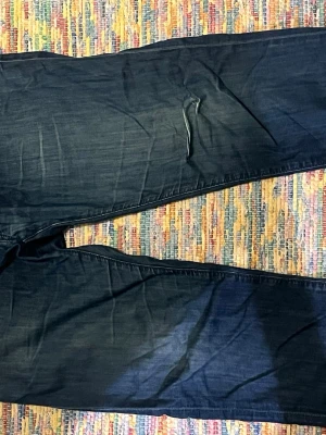 Mörkblå jeans med kontrastsömmar - Säljer ett par mörkblå jeans med raka ben och snygga kontrastsömmar. Klassisk femficksmodell med bälteshällor och knappgylf. Perfekta till vardags för en avslappnad men stilren look. Hittas oftast för ungefär 1600 begade men hos mig för ebdast 400 pga slitning.