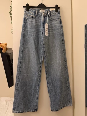 Blå low waist jeans  - Ljusblå jeans från Gina i modellen wide med pärldetaljer över hela framsidan. Jeansen är low waist och helt nya då det var fel storlek för mig. 