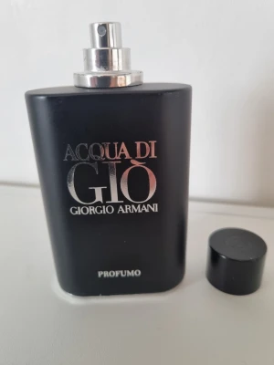 Acqua di Giò Profumo Giorgio Armani - Snygg parfymflaska i matt svart med silverdetaljer från Giorgio Armani. Acqua di Giò Profumo har en stilren, rektangulär form och tydlig logga framtill. Flaskan är tillverkad i glas och har en avtagbar svart kork. Perfekt för dig som gillar exklusiva dofter.