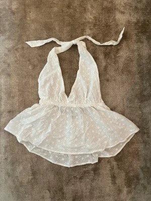 Somrig topp - Supergullig halterneck topp från Gina Tricot med broderade blommor. Knyte i nacken - kan justera hur tajt den ska sitta. Använd fåtal gånger. Inga anmärkningar 