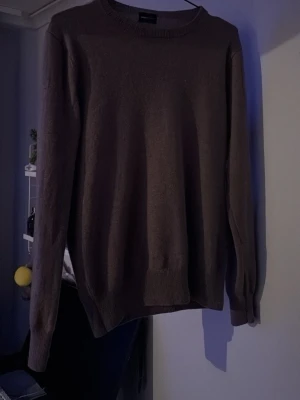 Brun stickad tröja från Swedish Fashion - En enkel och stilren brun stickad tröja från Swedish Fashion. Tröjan har rund halsringning, långa ärmar och ribbade muddar vid ärmslut och nederkant. Perfekt för lager på lager och passar till det mesta i garderoben.
