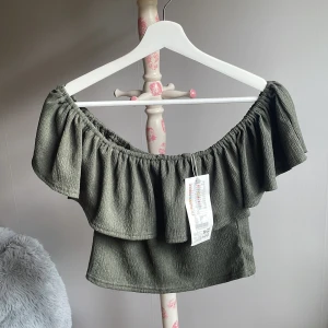 Grön offshoulder topp med volang - Snygg grön offshoulder topp med bred volang runt hela axelpartiet.