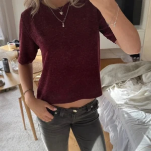 Vinröd croppad topp med kort ärm - Säljer en vinröd croppad topp med korta ärmar och rund hals. Toppens material känns mjukt och har en lätt melerad look. Passformen är normal och toppen är enkel att matcha med jeans eller kjol för en chill stil.