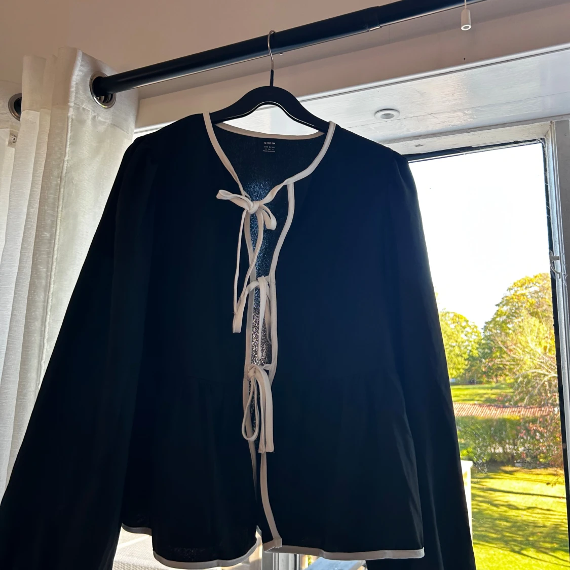 Svart kofta med vita knytband