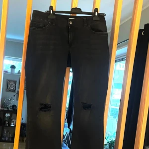 Svarta jeans med slitningar från Nelly - Svarta jeans från Nelly med snygga slitningar vid knäna och klassisk femficksdesign. Jeansen har en rak passform och är tillverkade i ett stretchigt bomullsmaterial som gör dem bekväma att bära hela dagen.