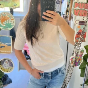 Vit kortärmad topp i bomull - Enkel och fräsch vit topp med korta ärmar och rund hals. T-shirten är i mjuk bomull och har en klassisk passform som funkar till jeans eller kjol. Perfekt för dig som gillar en clean och stilren look.