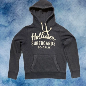 Blå Vintage Hollister Hoodie - Vintage och sällsynt Mörkblå Hoodie från Hollister med vit text på bröstet och klassik kängauruficka | Storlek M | Vintage och extremt svår att finna! |Går ner i pris vid snabbt köp! | Är 175, väger 70kg | Hör av vid ytterligare frågor!!!