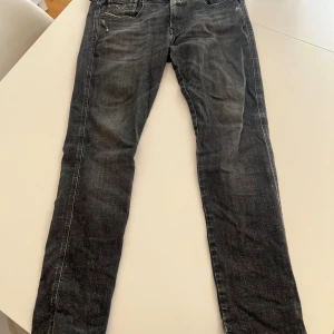 Replay Anbass svart/ grå jeans - Säljer ett par Replay Anbass jeans i svart/ grå tvättad färg med slitningar.