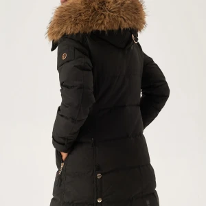 Svart lång dunjacka med päls - Säljer en svart dunjacka från Hollies med lång passform och snygg pälsimitation på huvan. Jackan har silverfärgade knappar, dragkedjor på fickorna och detaljer på ärmsluten. Perfekt för kalla dagar och har en riktigt chill vibe. OBS! Loggan på armen är bort och den är använd men i bra skick.  Material: Yttermaterial: 90% Polyester, 10% Bomull Foder: 100% Polyester Fyllning: 80% Dun, 20% Fjäder 