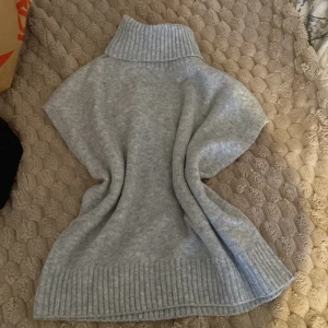 Grå stickad polotröja med kort ärm - Säljer en ljusgrå stickad polotröja med bred ribbad krage och nederkant. Tröjan har korta ärmar och är gjord i mjukt material som känns skönt mot huden. Perfekt för lager-på-lager och chill stil. Passar dig som gillar enkel och clean look. Oanvänd. Säljer då jag inte tycker om den. 