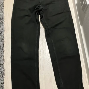 Svarta byxor från Xdye, XS 28 - Svarta jeans från Xdye med elastisk midja och raka ben. Byxorna har en enkel bakficka och är tillverkade i ett mjukt bomullsliknande material. 