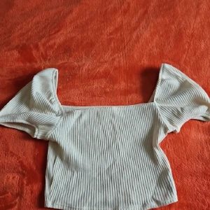Vit ribbad offshoulder topp - Säljer en vit ribbad topp med offshoulder och korta puffärmar. 