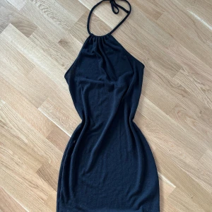 Svart klänning  - Svart kortklänning med knyt i nacken. Storlek S, lite genomskinlig 
