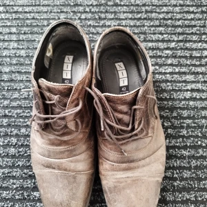 Bruna skinnskor från XIT, storlek 42 - Säljer ett par bruna skinnskor från XIT i storlek 42. Skorna har snörning, rund tå och en klassisk design med diskreta sömmar. Perfekta för dig som gillar en stilren look med vintagekänsla. Passar till både jeans och chinos.