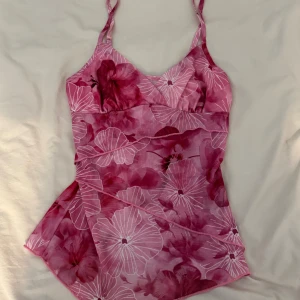 Rosa blommigt linne med smala axelband från SHEIN  - Snyggt linne i rosa med blommigt mönster och smala axelband. Modellen har en lätt utsvängd form och v-ringad hals. Materialet känns mjukt och följsamt. Blommorna är i olika nyanser av rosa och vitt för en fräsch sommarkänsla.