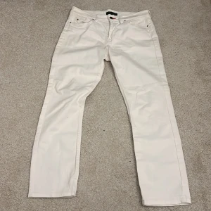 Vita raka jeans från Tommy Hilfiger - Snygga vita jeans från Tommy Hilfiger med raka ben och klassisk femficksdesign. Byxorna har diskreta logodetaljer, silverfärgade nitar och knapp, samt broderi på bakfickorna. Tillverkade i bomull för en skön känsla och stilren look. 41cm bredd och 96cm längd gör av er vid fler frågor 😊🙌🏼