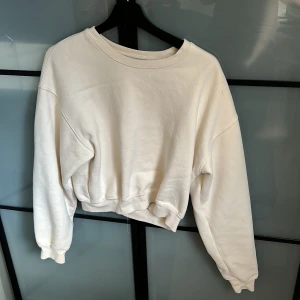 Vit croppad sweatshirt från BikBok - Säljer en vit croppad sweatshirt från BikBok i storlek XS. Tröjan har rund hals, långa ärmar och ribbade muddar. Perfekt basic att ha i garderoben och lätt att matcha med allt. Mjuk och skön med avslappnad passform.