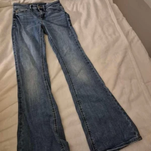 Blå bootcut jeans från Vero Moda - Snygga blå bootcut jeans från Vero Moda med klassisk femficksdesign och ljus tvätt. Jeansen har normal passform och är tillverkade i jeansmaterial. Perfekta för dig som gillar en retroinspirerad look med utsvängda ben.