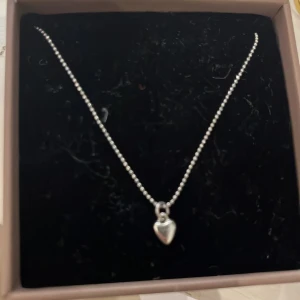 Silverhalsband med hjärta från Edblad - Supersnyggt halsband från Edblad i silverfärg med ett litet hjärtformat hänge. Kedjan är tunn och består av små kulor som ger en stilren och modern look. Perfekt accessoar för att lyfta vilken outfit som helst.