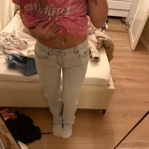 Ljusgrå raka jeans med låg midja - Säljer ett par ljusgrå jeans med låg midja och raka ben. Jeansen har klassiska fem fickor och tydliga sömmar. Perfekta för dig som gillar en clean och enkel look.