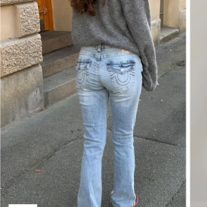 True Religion ljusblå bootcut jeans - Ljusblå bootcut jeans från True Religion , röda sömmar och slitningar på låret. Jeansen är mid waist men ser ut som low waist på. Pris kan diskuteras, skriv gärna för frågor eller fler bilder.