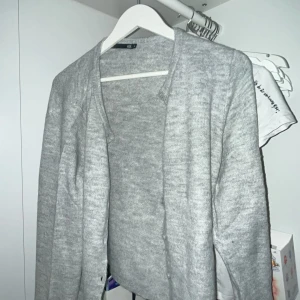 Ljusgrå kofta från 157, storlek M - Mysig ljusgrå kofta från 157 i storlek M. Koftan är stickad med långärmad design och har en enkel, öppen front utan knappar. Perfekt för lager-på-lager och chill dagar. Passar dig som gillar en clean och basic stil. Helt oanvänd bara testat den var för stor 