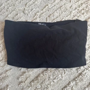 Svart bandeau tubtopp - En enkel svart bandeau tubtopp i mjukt bomullsmaterial. Toppen är ärmlös och axelbandslös